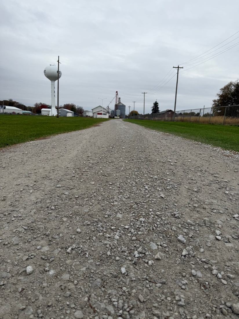 Gravel road leading toward a water tower and grain elevator