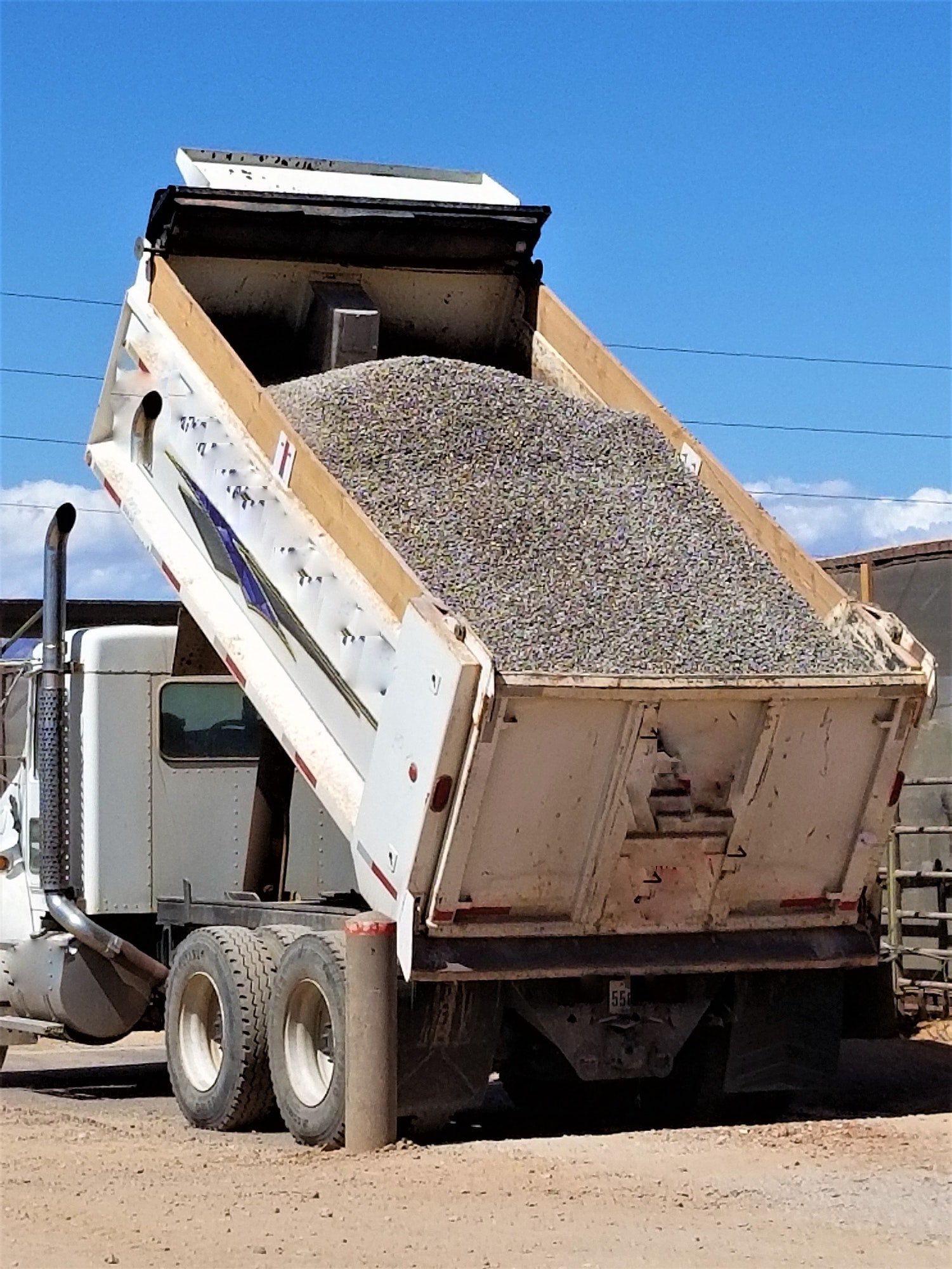 Dump truck delivering sand and gravel in Stuart, Iowa